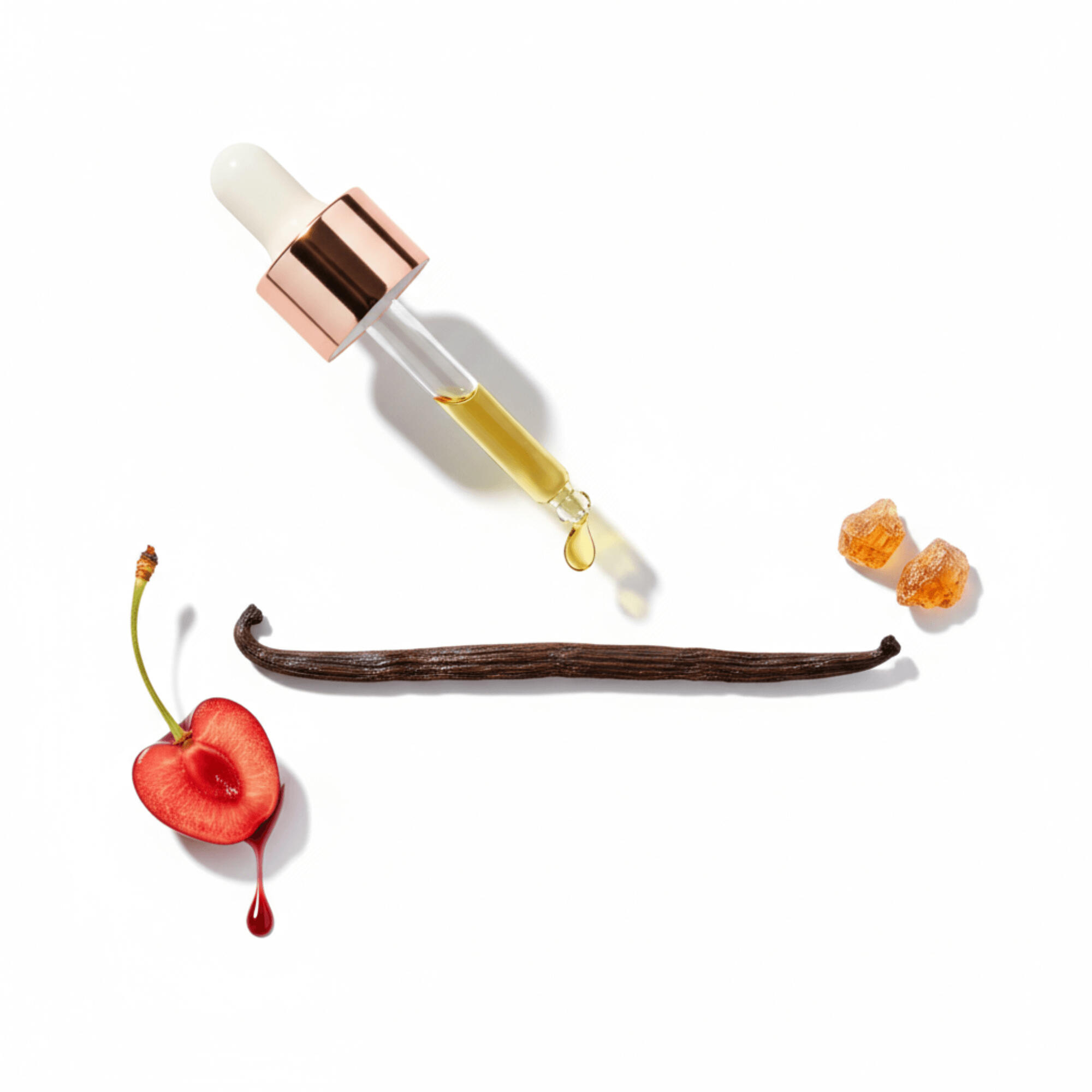 A clean editorial flat lay showing the core ingredients of MODA Dolcezza Vanilla Infini: a dropper releasing golden jojoba oil above a whole vanilla bean, a sliced cherry with juice dripping, and two pieces of benzoin resin, all arranged on a white backgro